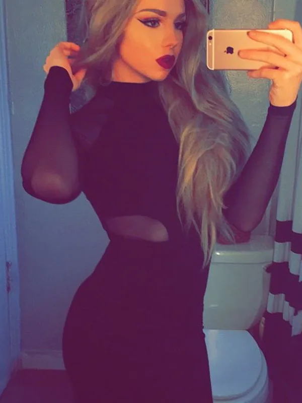 Femme aux cheveux blonds prenant un selfie dans une salle de bain avec une robe noire et un téléphone rose doré.